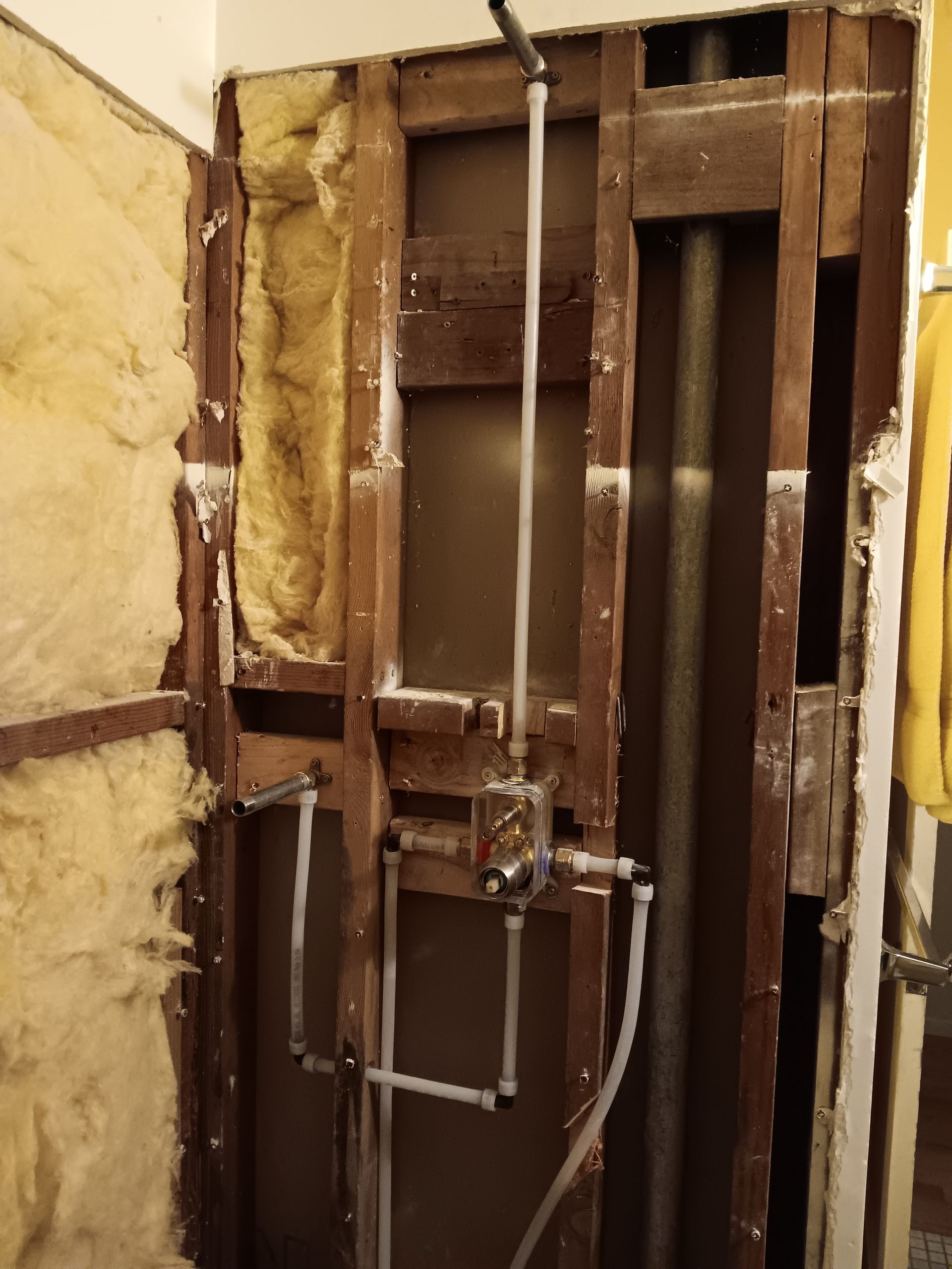 Exposed wall framing with insulation and electrical wiring in a partially renovated room