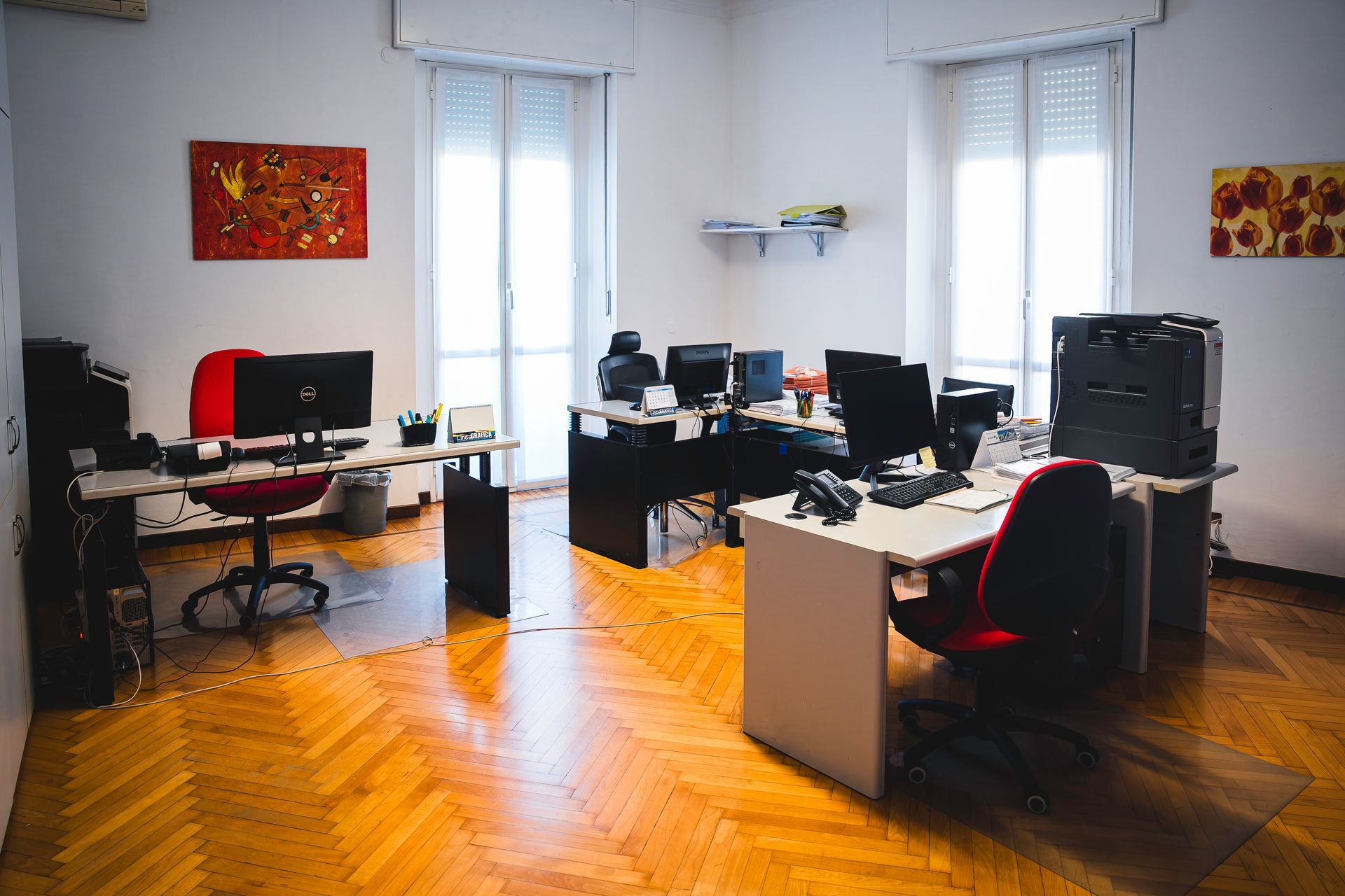 Clessidra su una scrivania di legno, con la sabbia che scorre verso il basso. Libri e penne sullo sfondo sfocato.