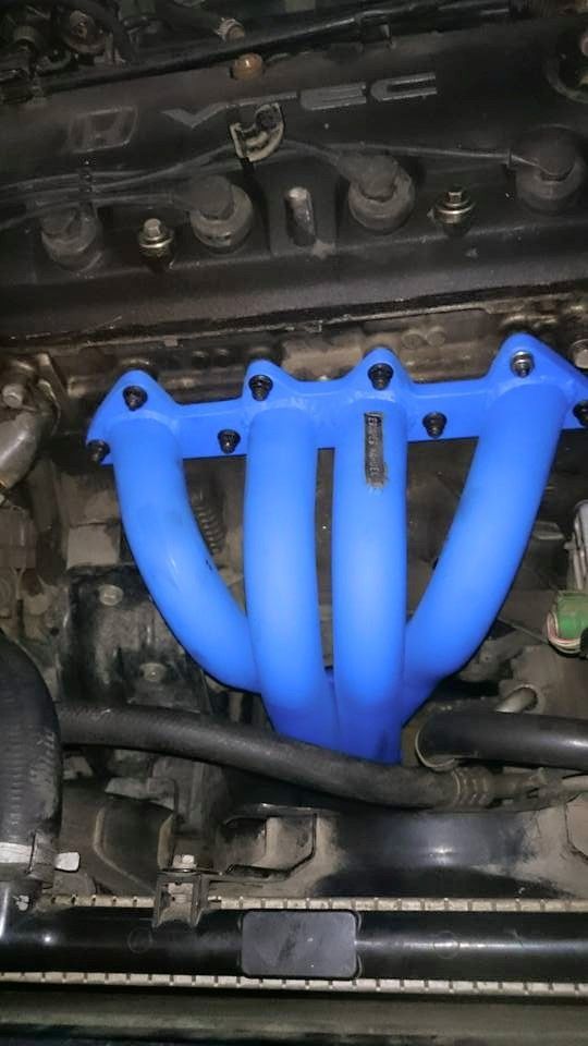 Un colector de escape azul está situado encima del motor de un automóvil.