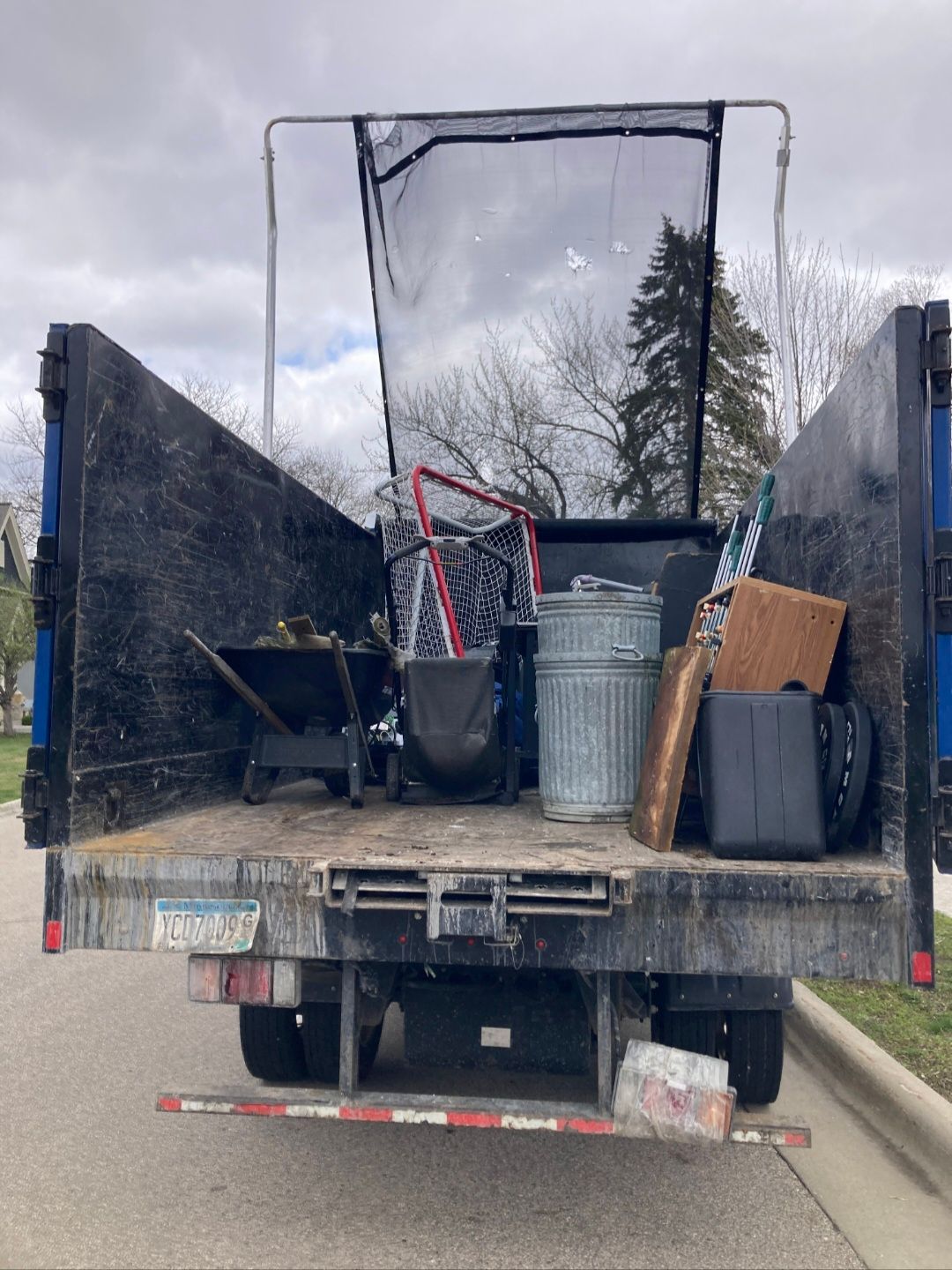 A dump truck filled with junk is parked on the side of the road.