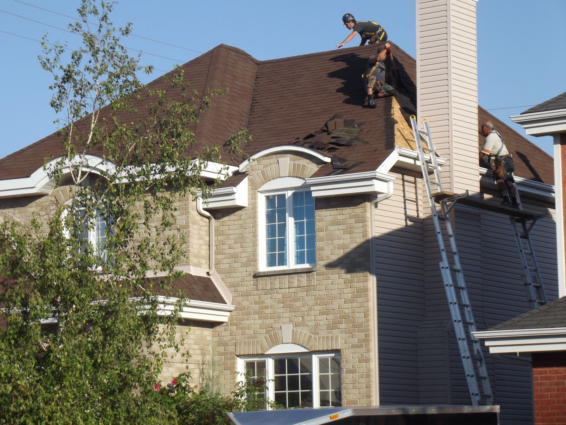 Two men are working on the roof of a house