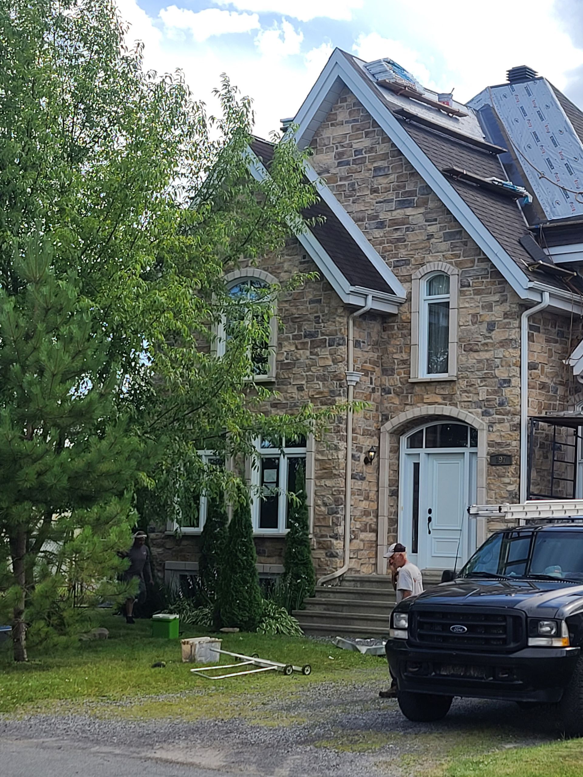Un camion est garé devant une grande maison en pierre.