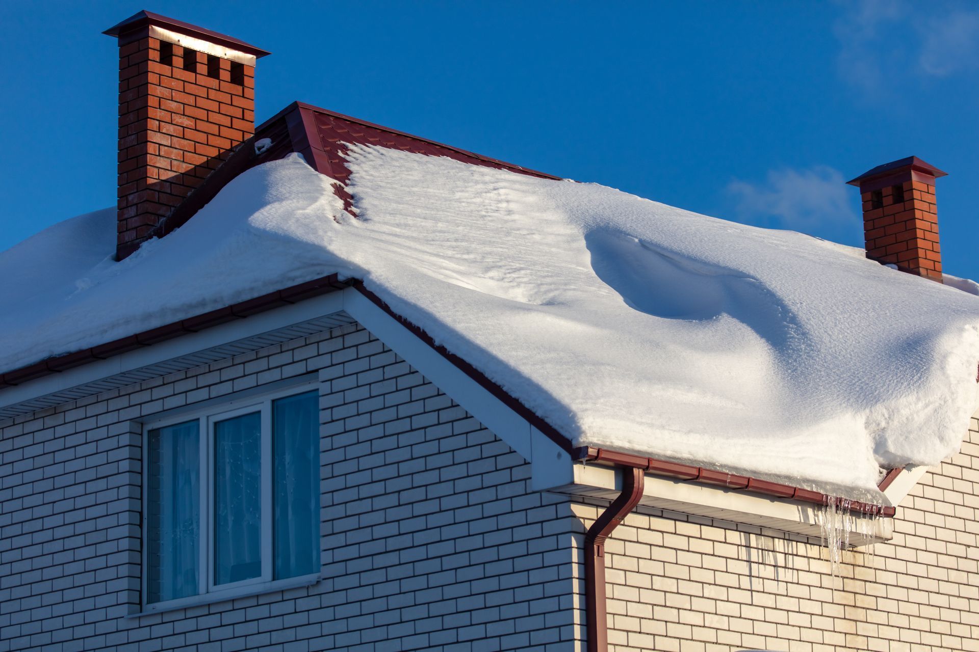 A white brick house with snow on the roof