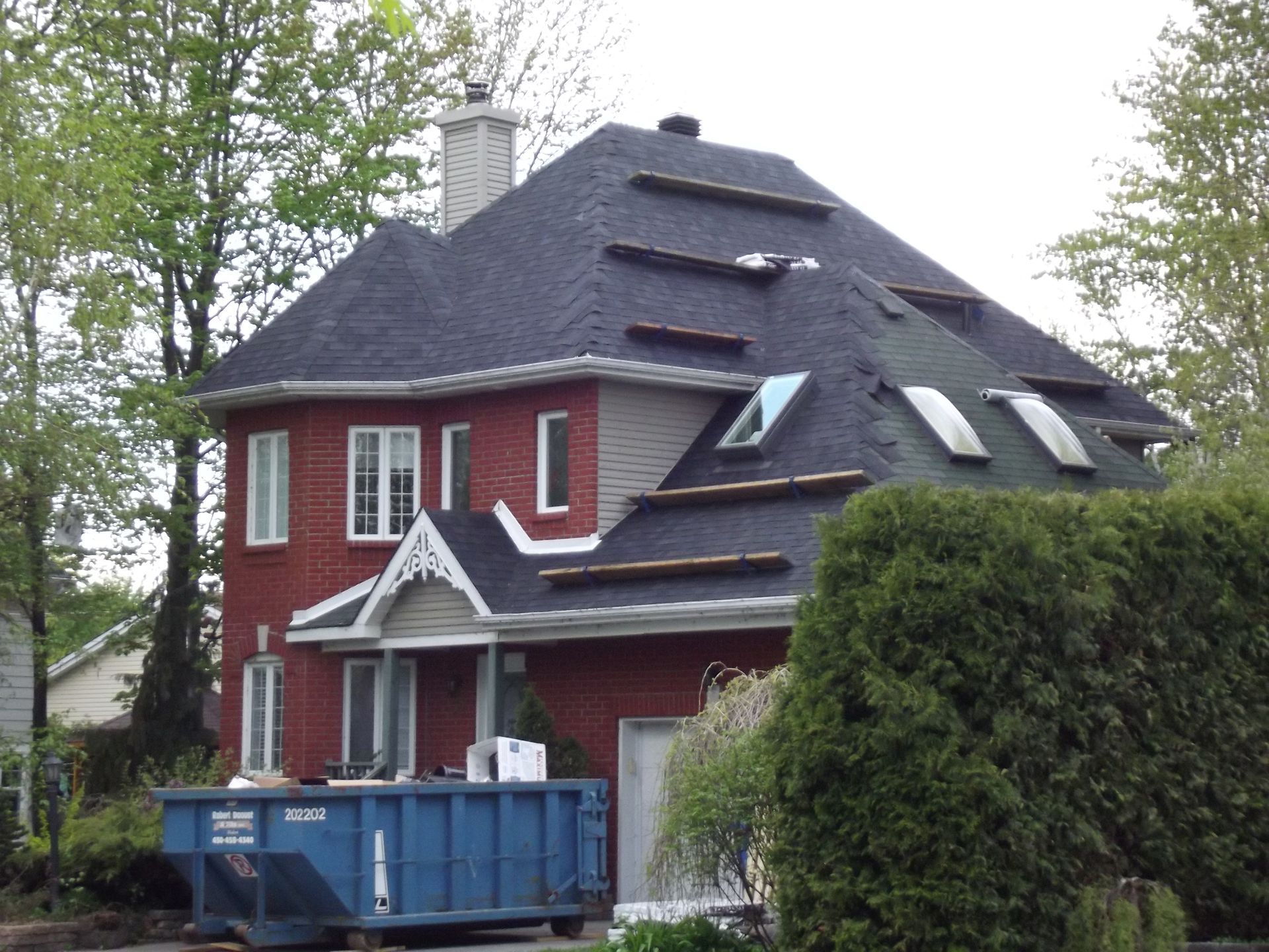 A red house with a blue dumpster in front of it