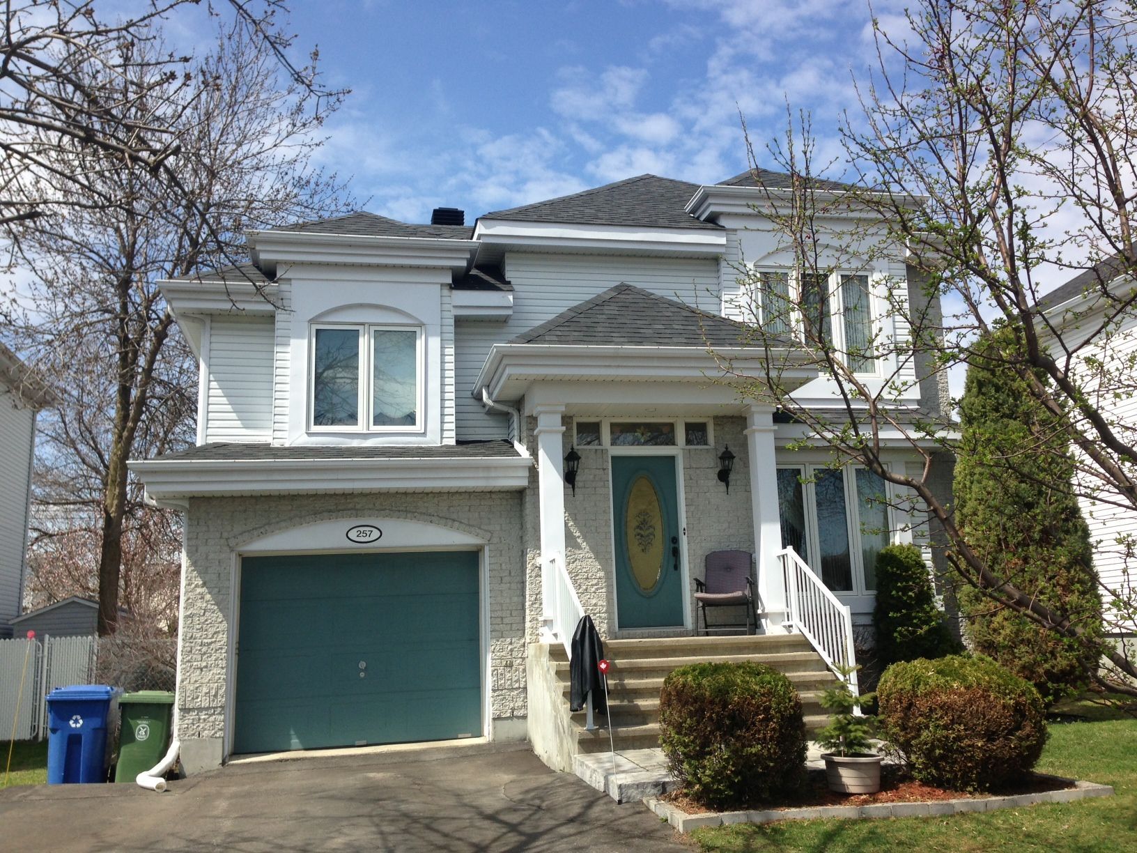 A white house with a green garage door and stairs
