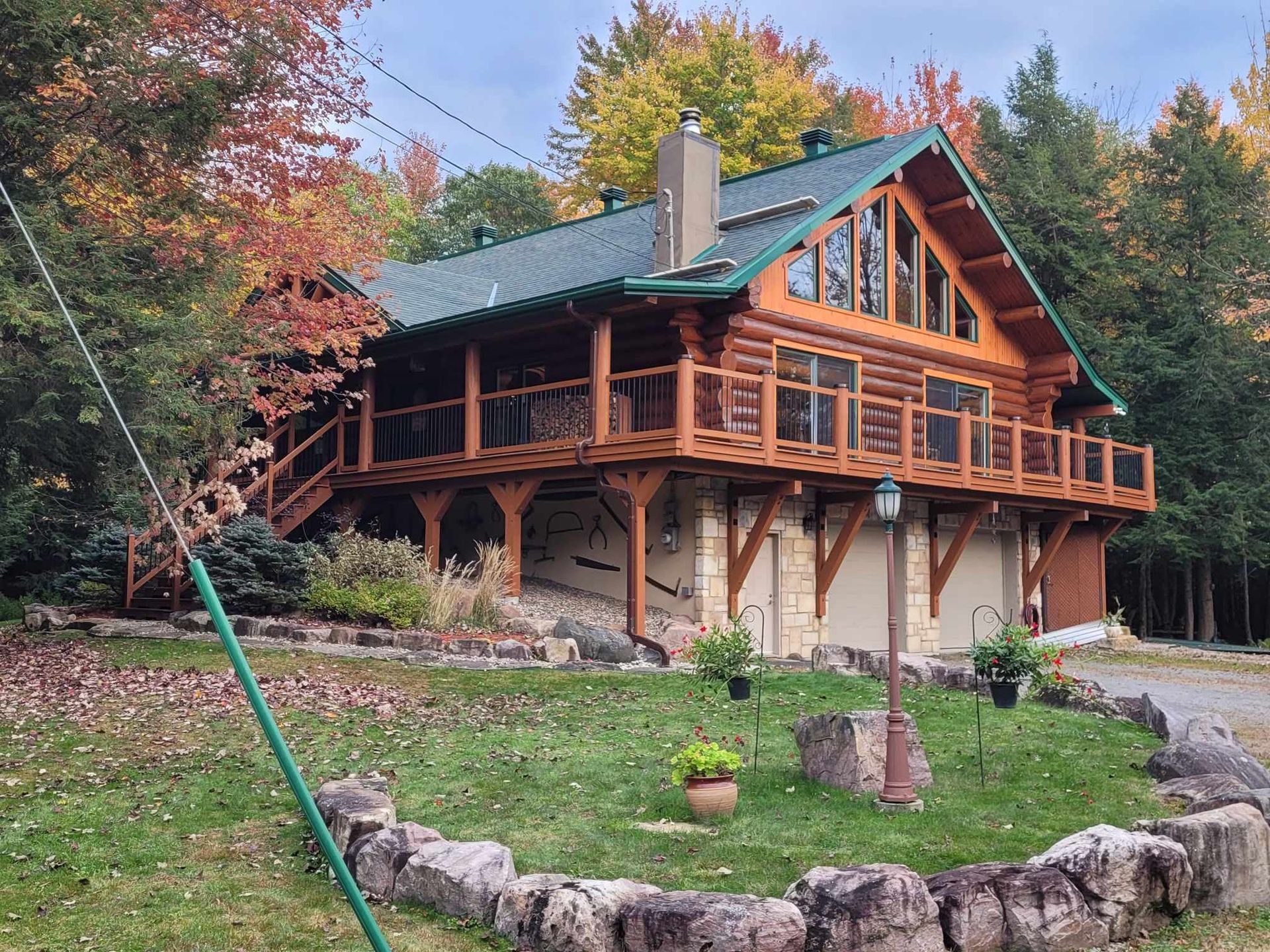 Une grande cabane en rondins avec un toit vert est entourée d'arbres.