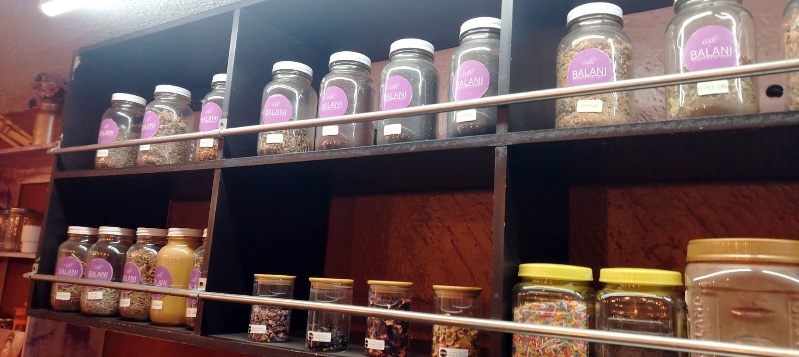 Estantes llenos de frascos de especias en una tienda. Las etiquetas son visibles y los frascos contienen hierbas y condimentos.