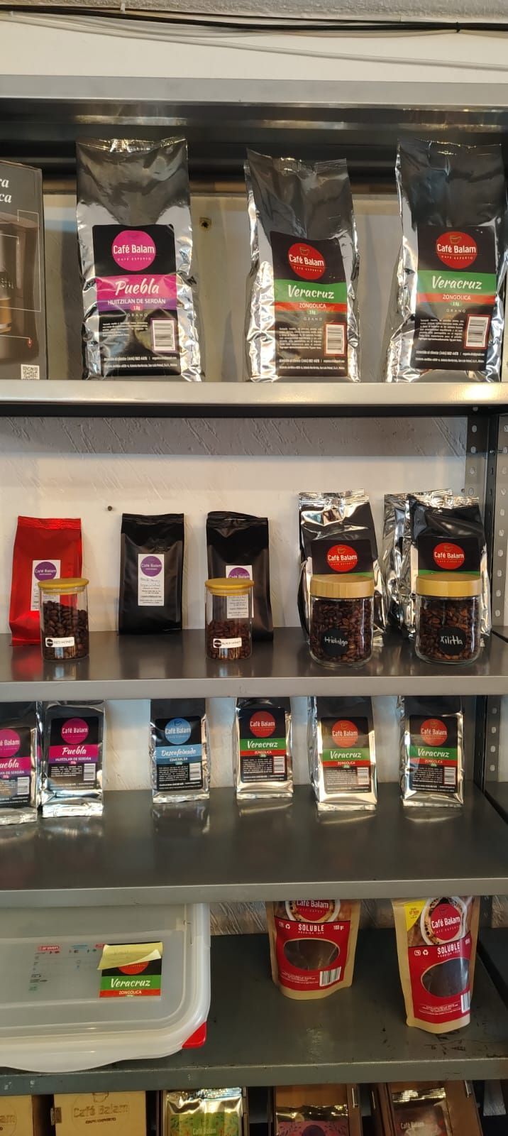 Estantes llenos de diversas bolsas y recipientes de café en una tienda.