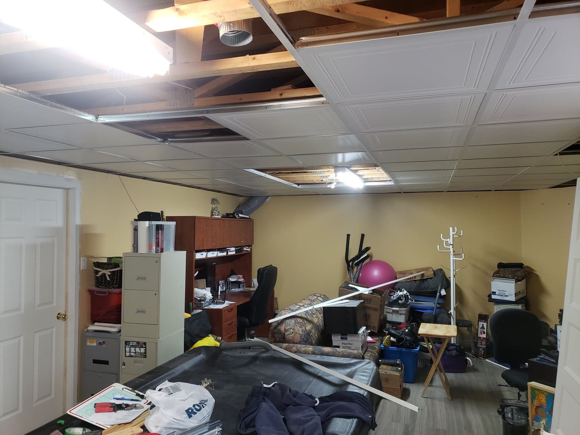 Une pièce en désordre avec un plafond qui a été endommagé par une tempête.