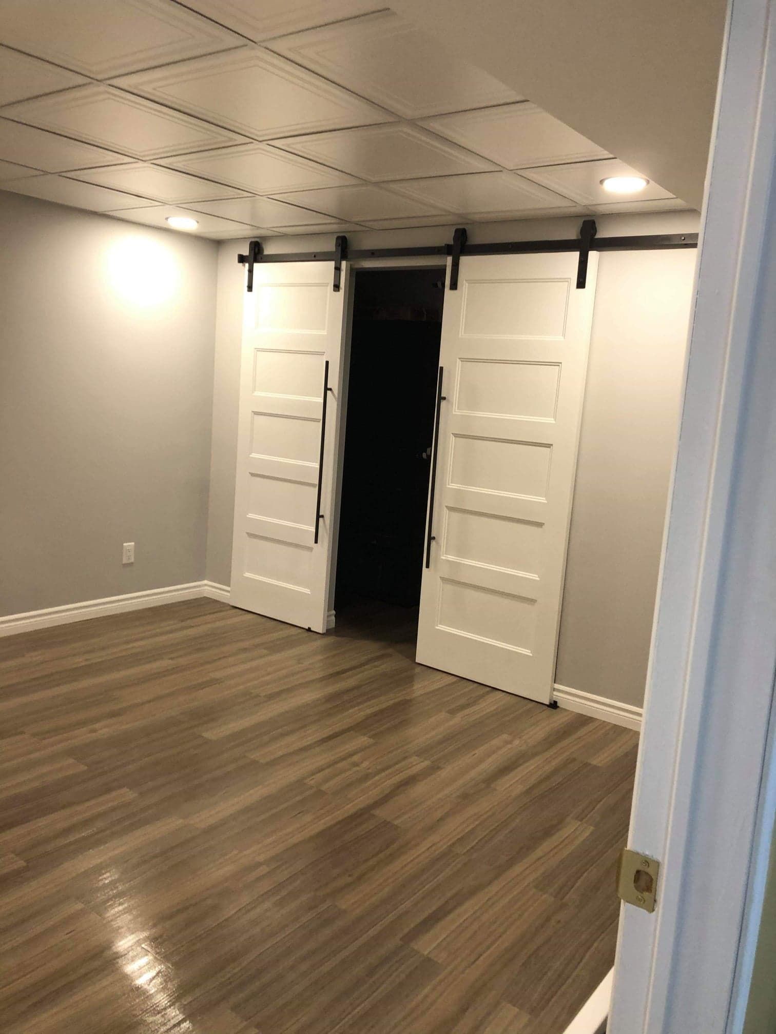 Un sous-sol avec portes de grange coulissantes et planchers de bois franc.