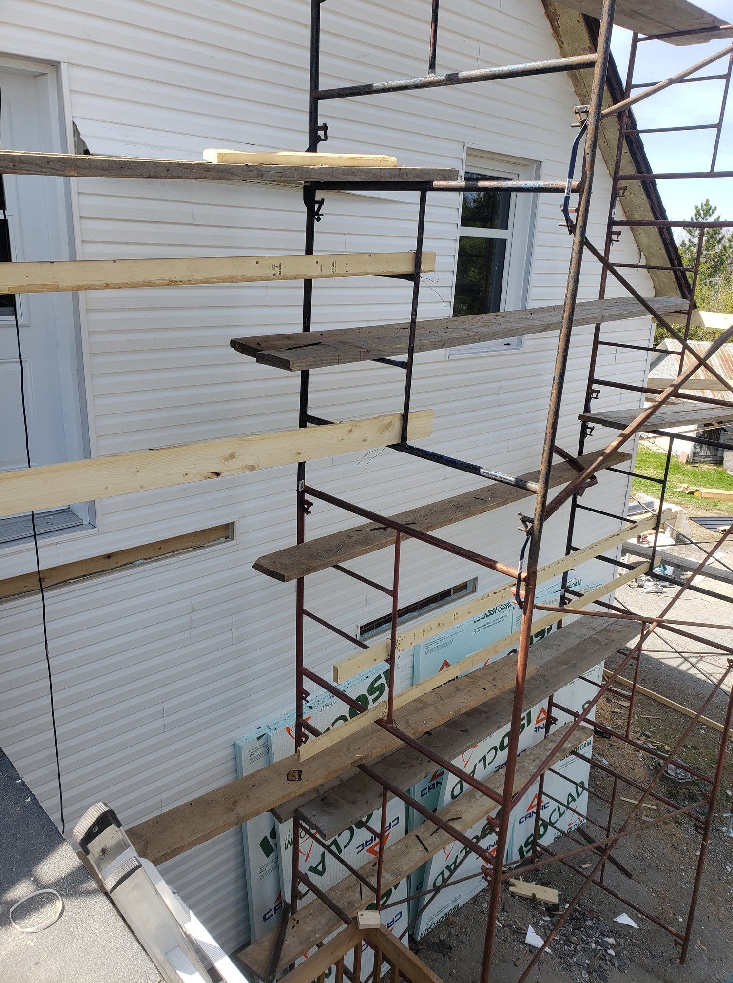 Un échafaudage est posé devant une maison blanche.