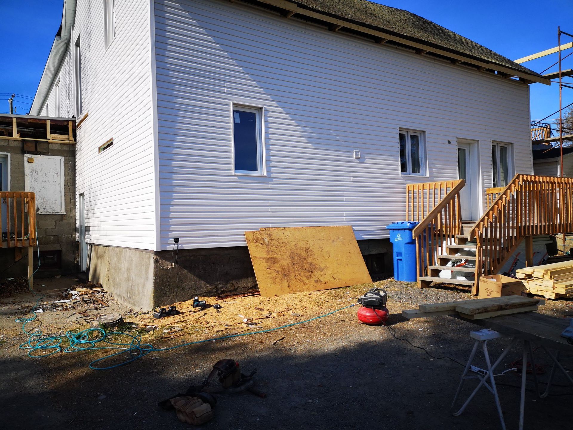 Une maison blanche avec des escaliers et une échelle devant elle