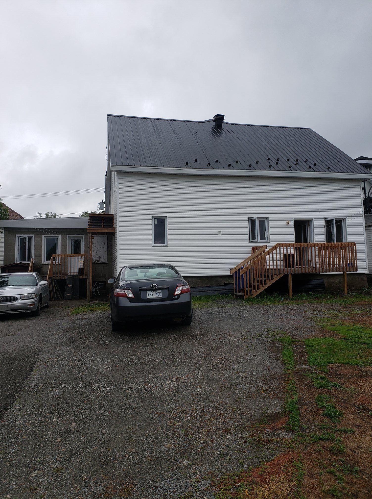 Une voiture noire est garée devant une maison blanche.
