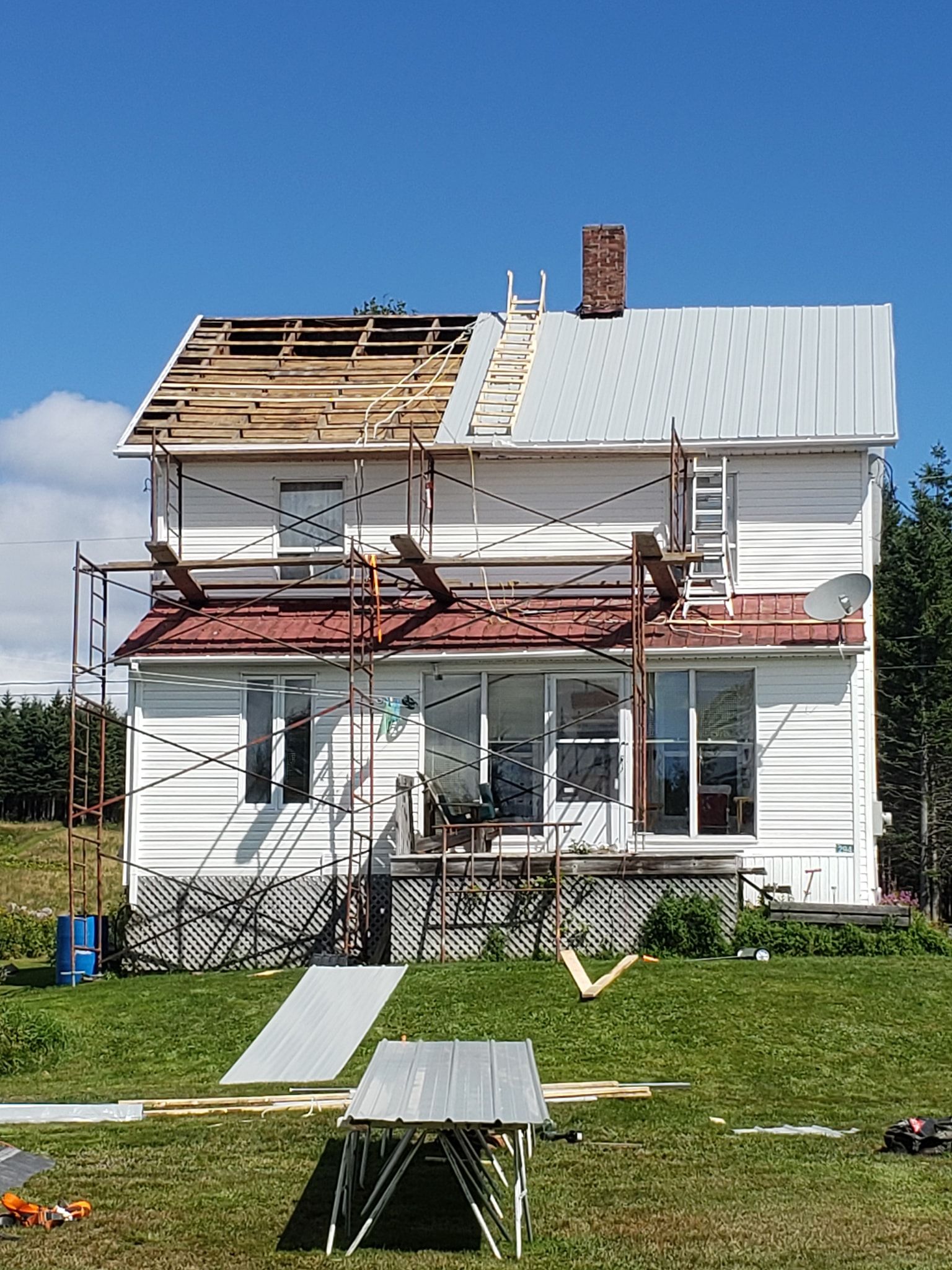 Une maison blanche avec un toit rouge est en cours de rénovation