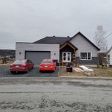 Une maison avec deux voitures garées devant