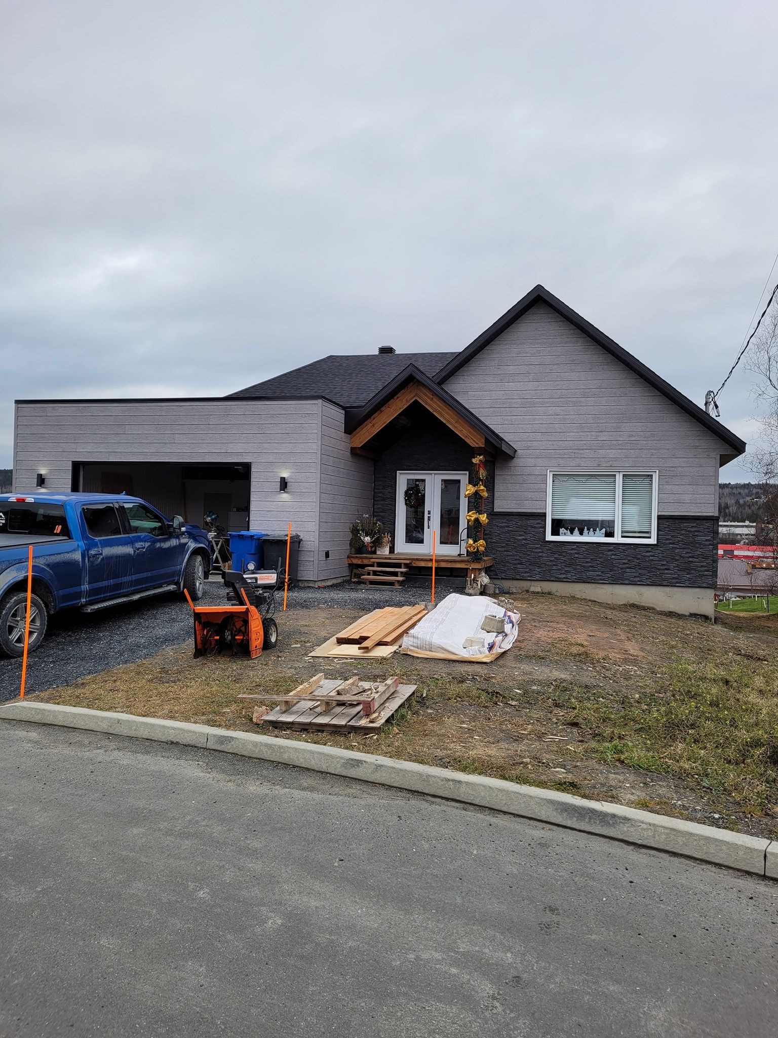 Un camion bleu est garé devant une maison en construction.