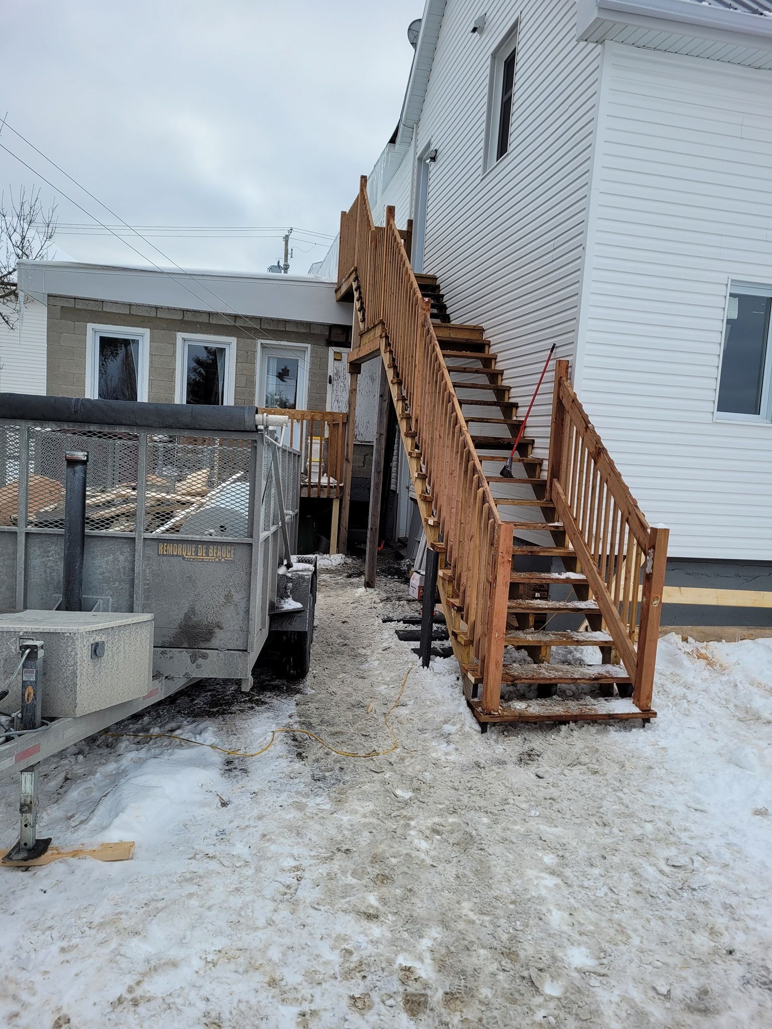 Un escalier en bois menant à une maison sous la neige.