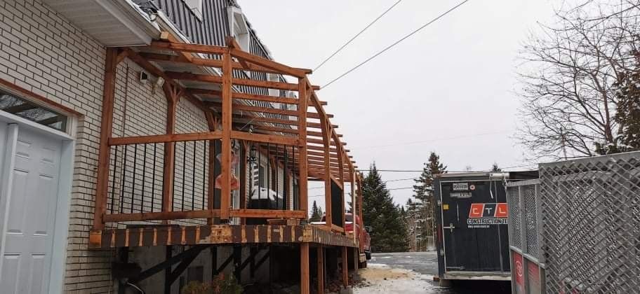 Une terrasse en bois est en cours de construction sur le côté d'une maison.