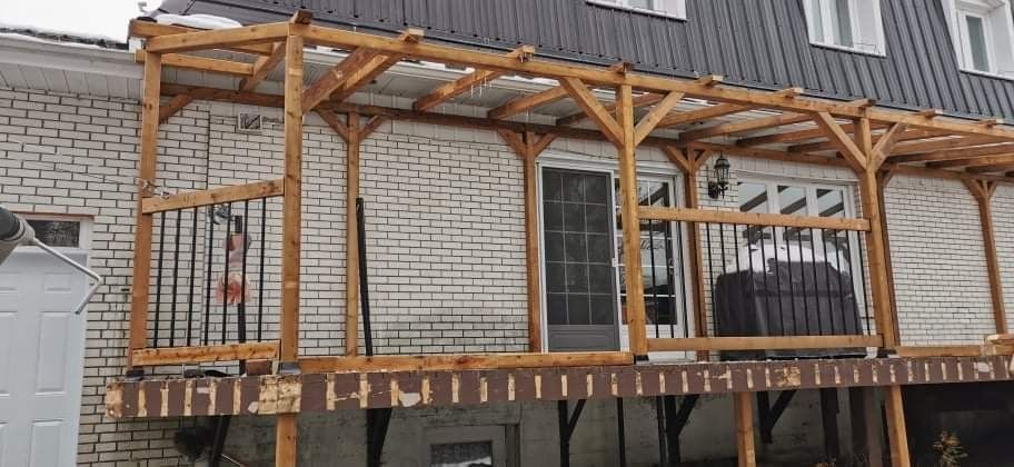 Une terrasse en bois est posée sur le côté d'une maison en briques.