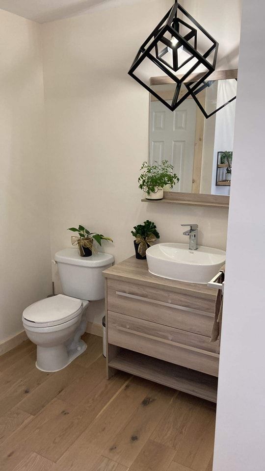 Une salle de bain avec WC, lavabo et miroir.