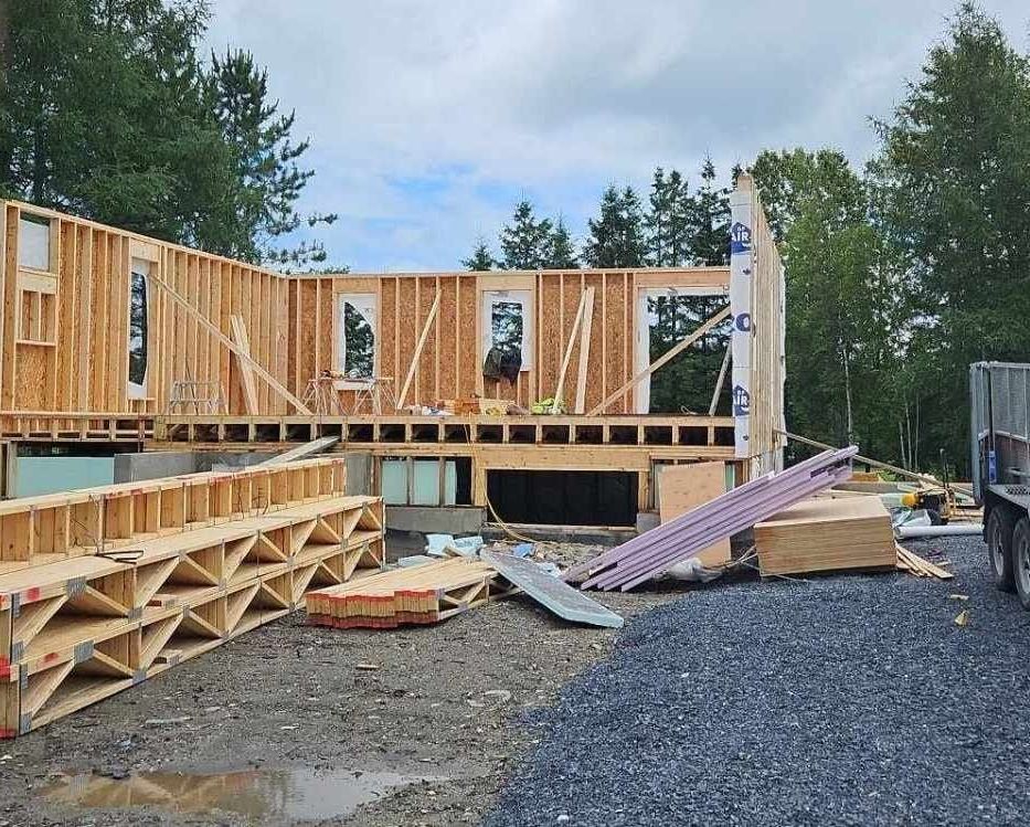Une grande structure en bois est en cours de construction sur un chemin de terre.