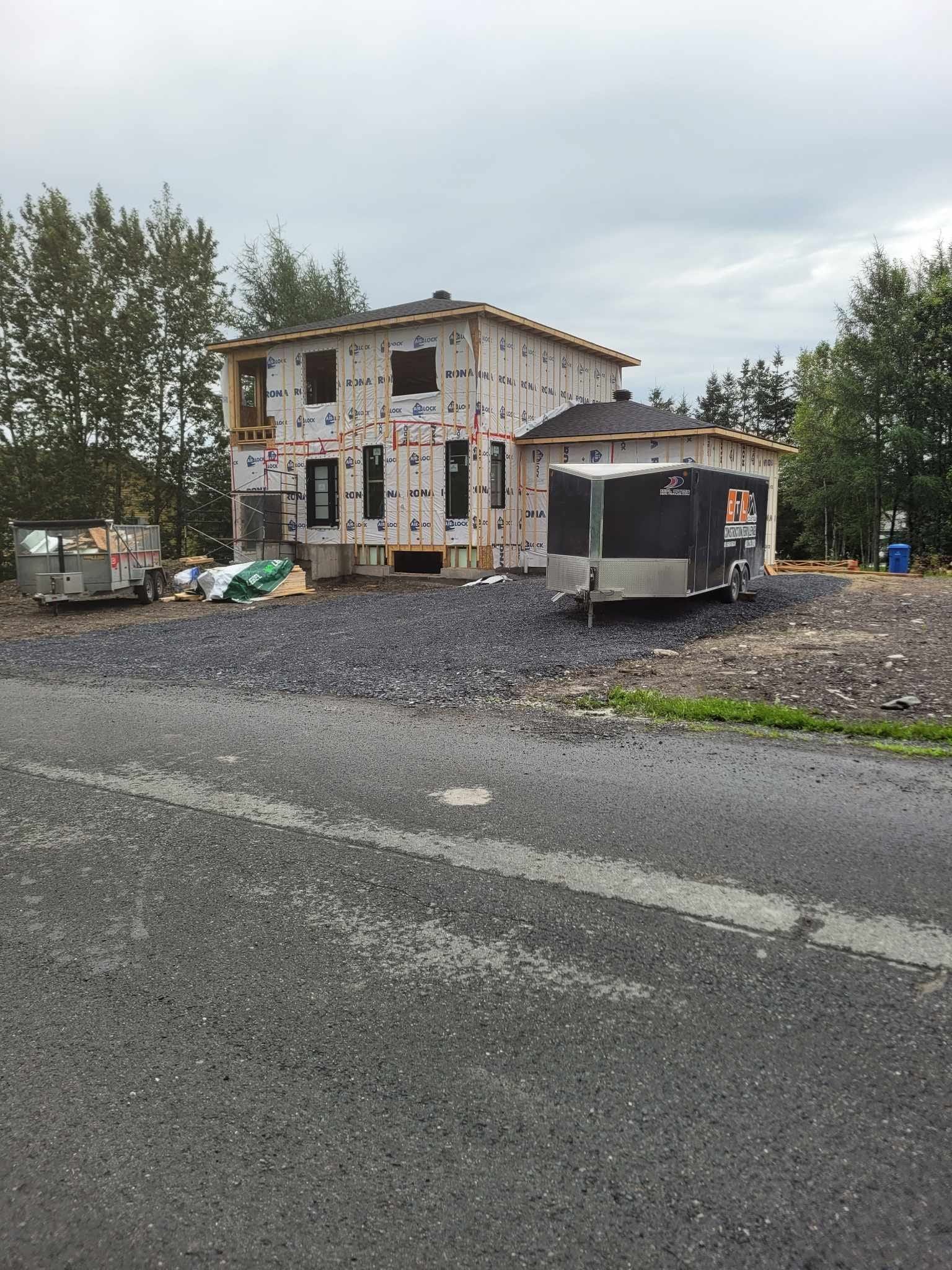 Une maison est en construction sur le bord de la route à côté d'une caravane.