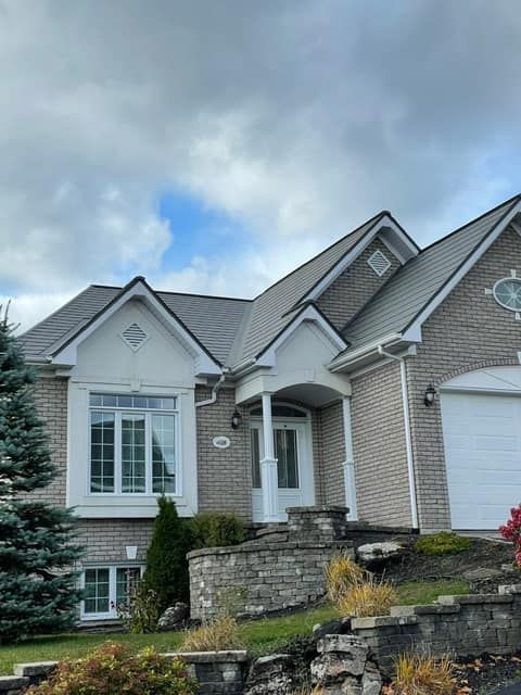 Une grande maison en brique avec un toit gris et une porte de garage blanche.