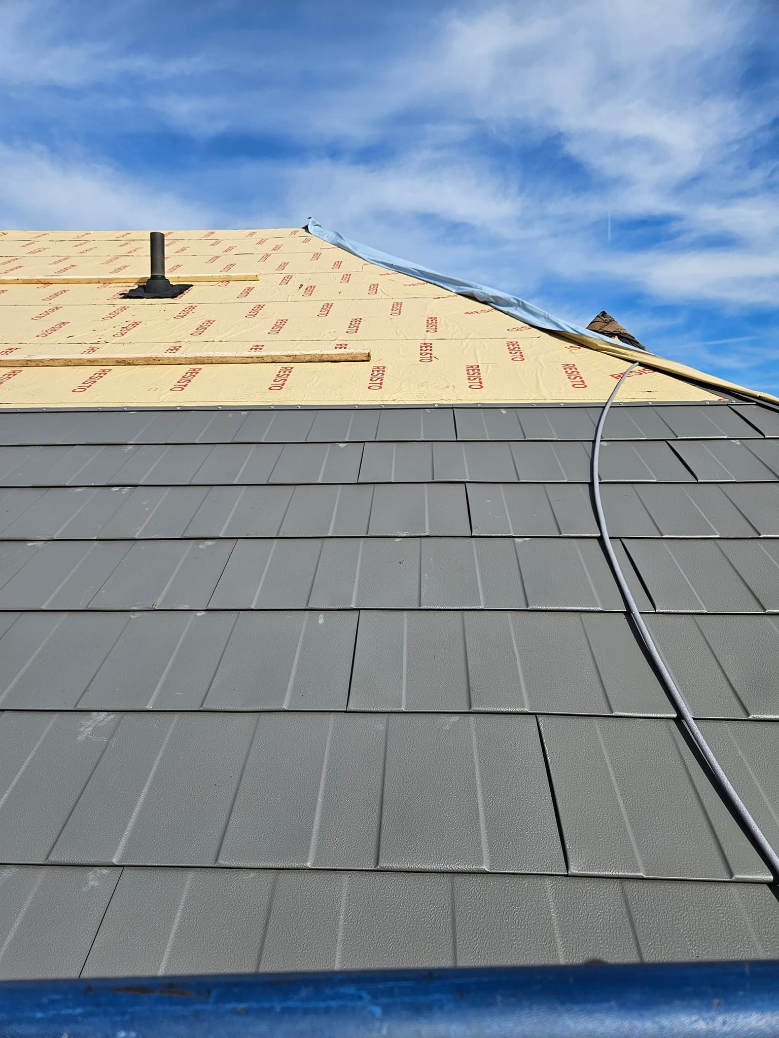 Le toit d'une maison est en train d'être construit et les bardeaux sont en train d'être installés.