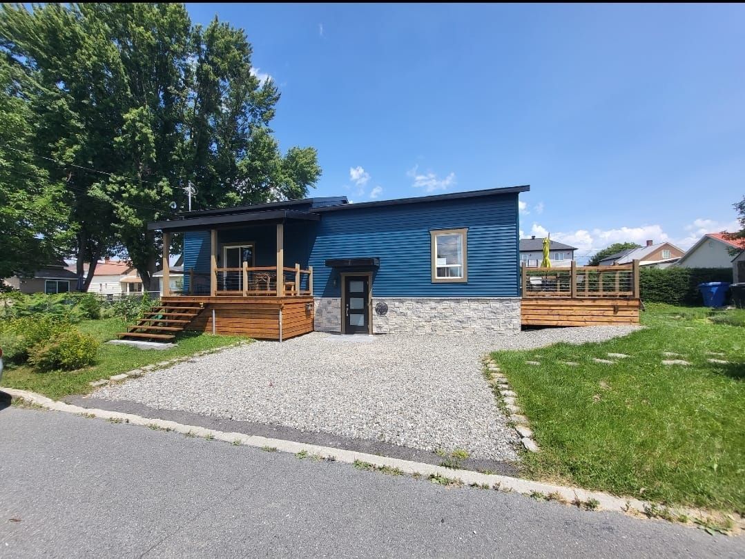 Une petite maison bleue avec un porche et une allée de gravier.