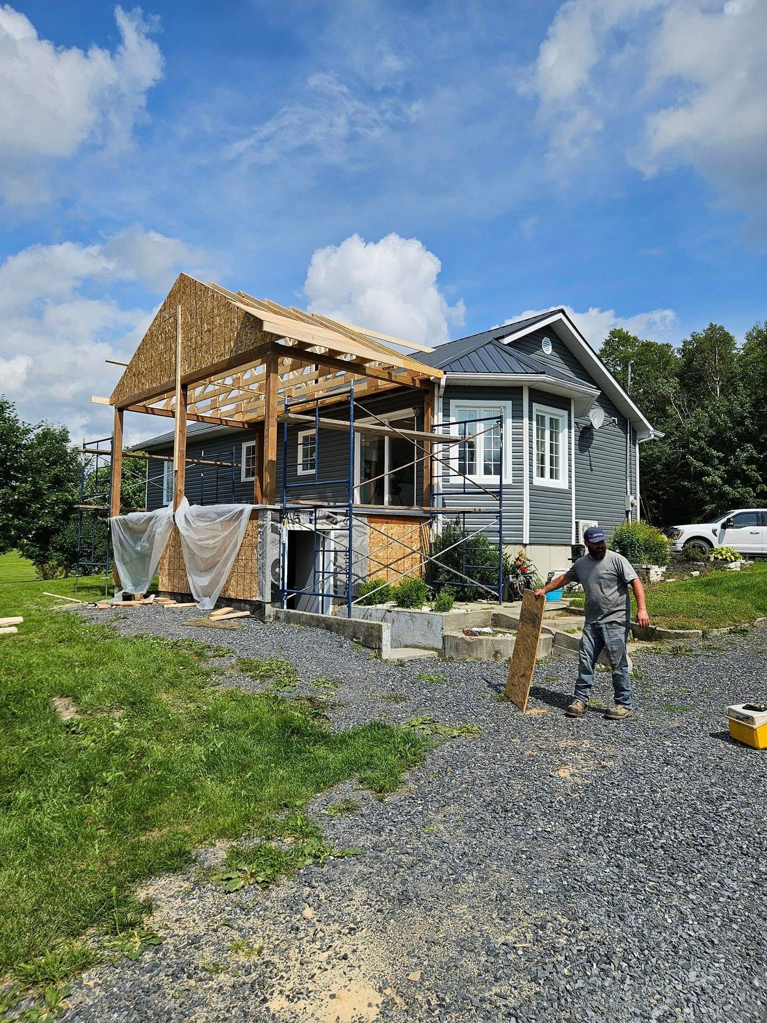 Un homme se tient devant une maison en construction.