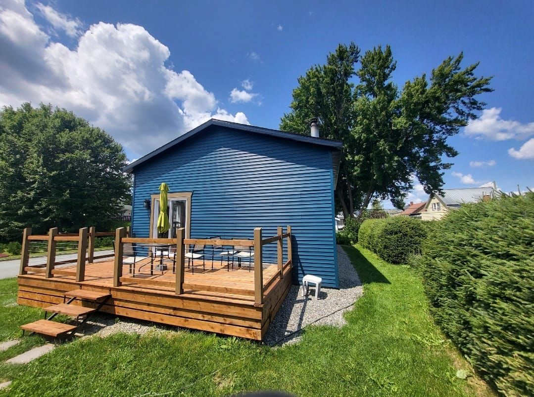Une petite maison bleue avec une terrasse en bois devant.