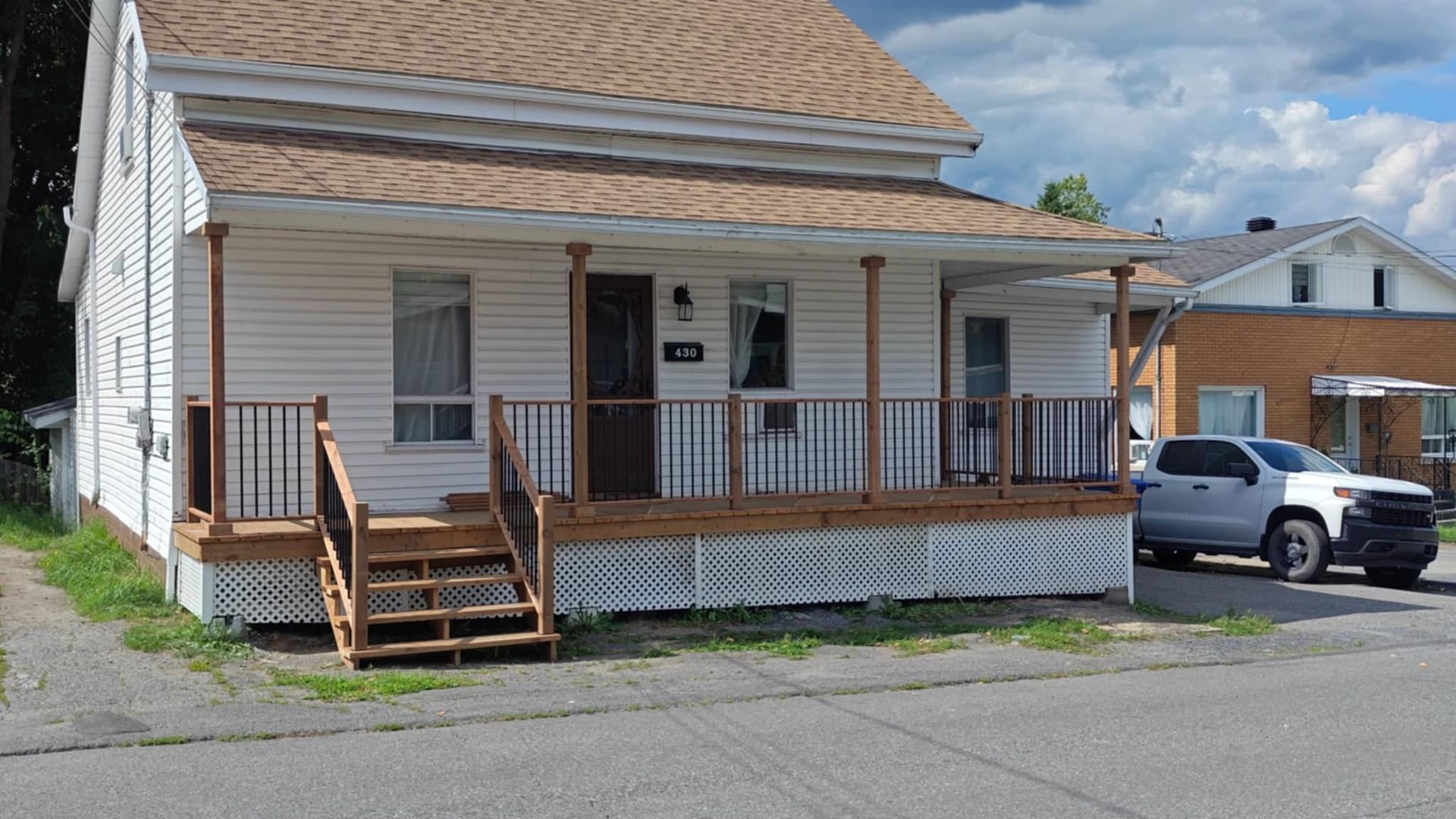 Une maison blanche avec un porche et un camion garé devant.