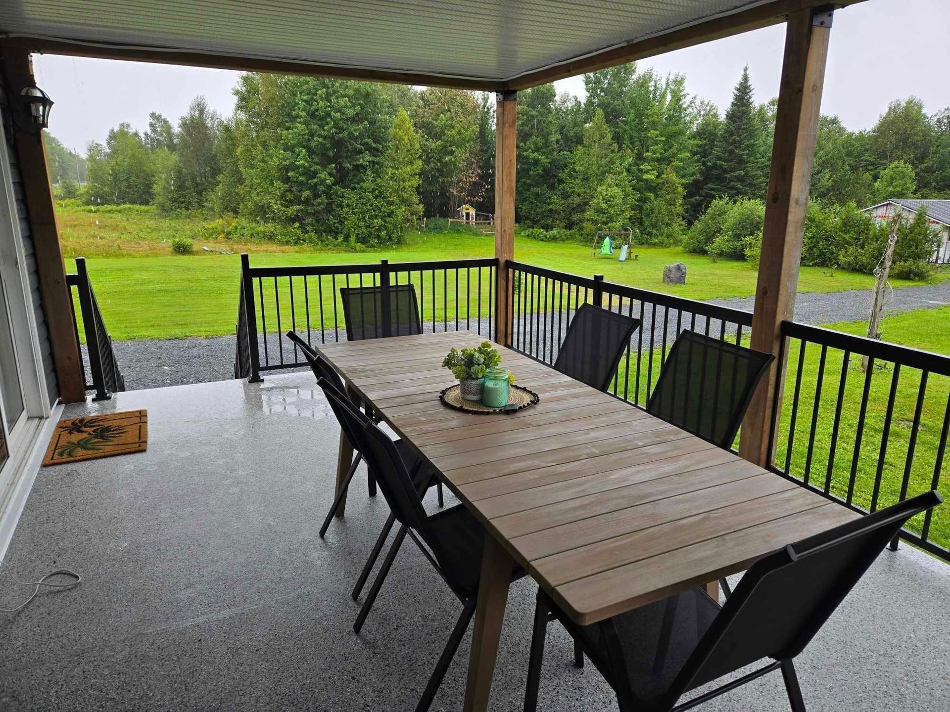 Une terrasse avec une table et des chaises pour un jour de pluie.