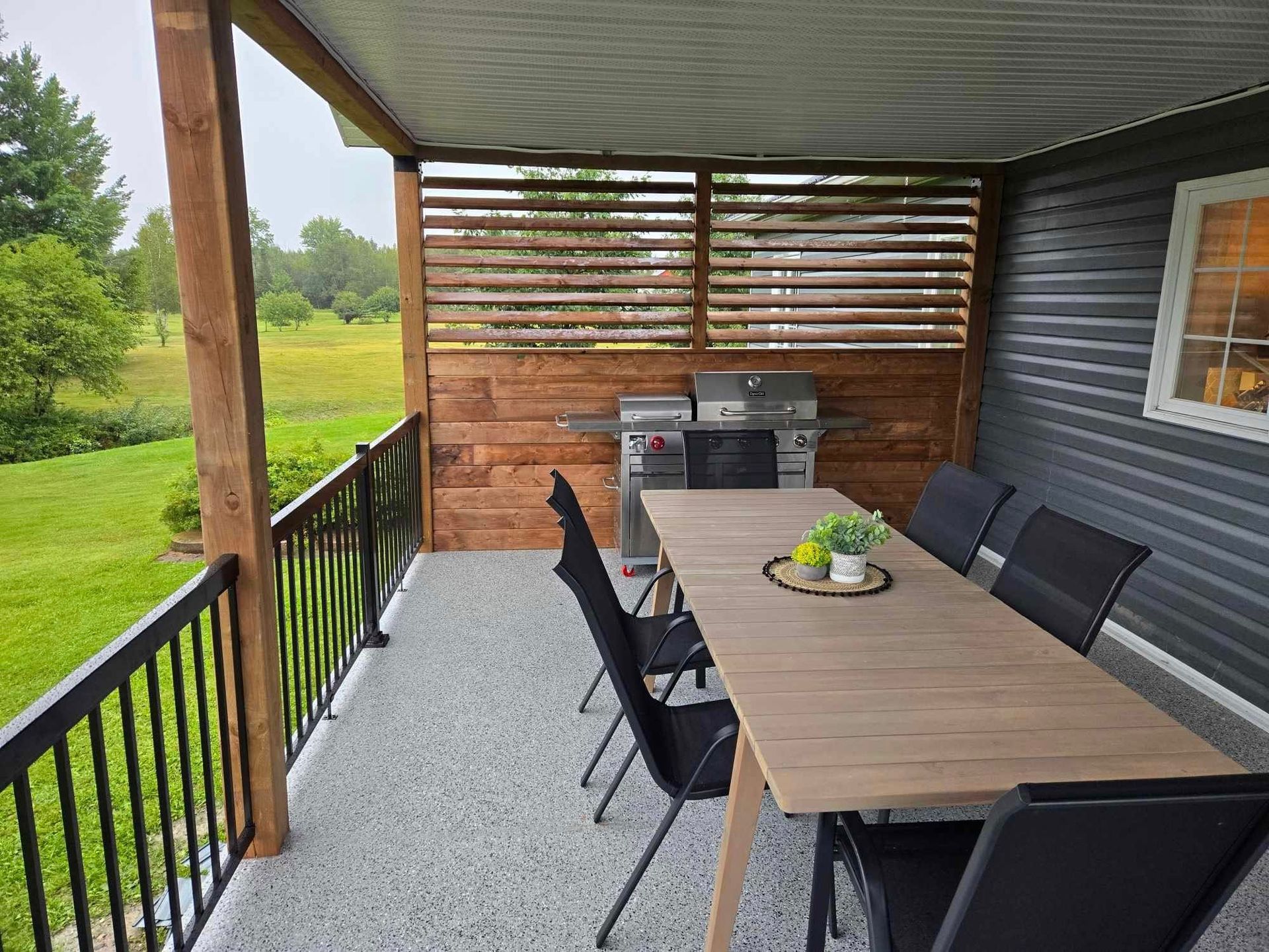 Un porche avec une table, des chaises et un grill.