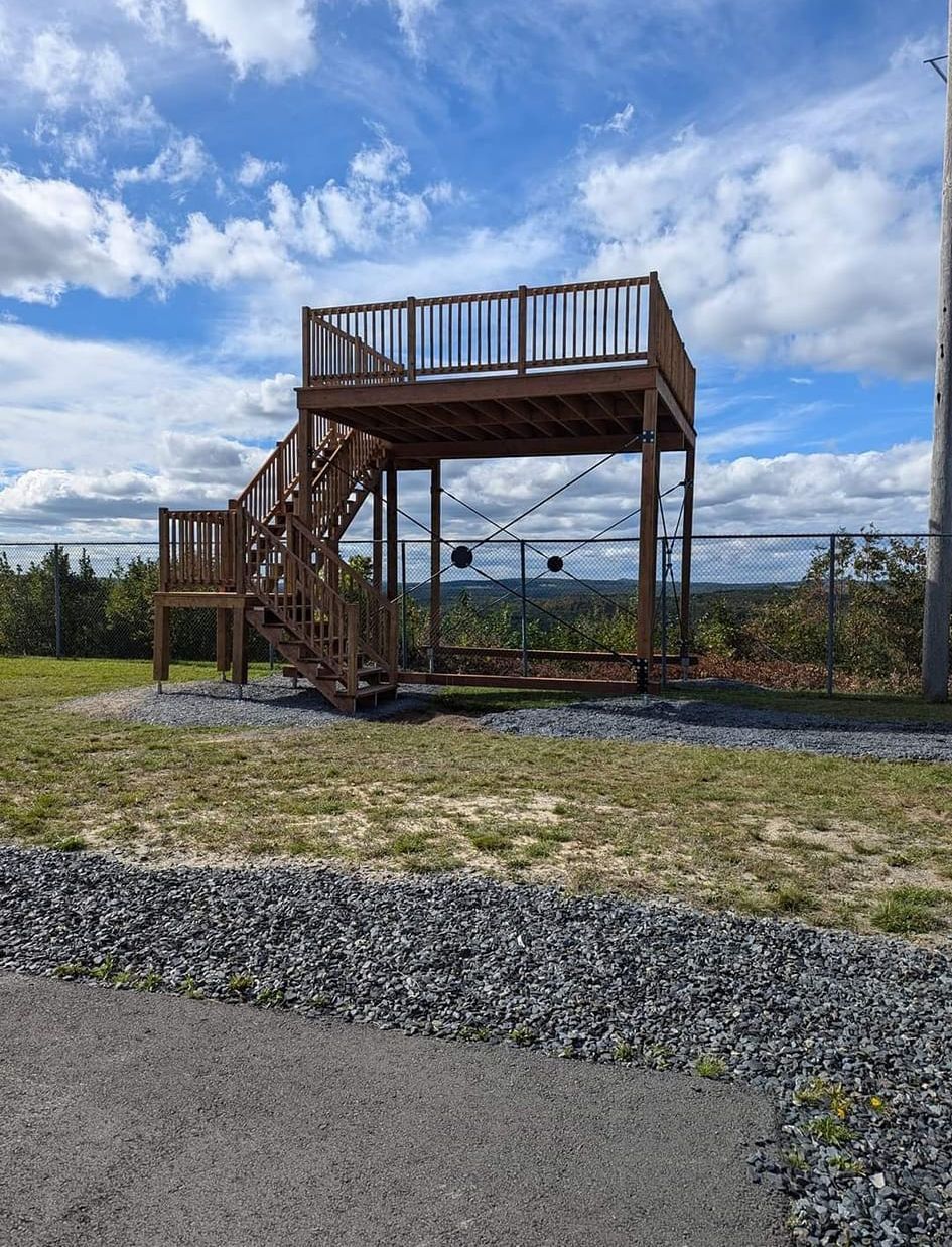 Une terrasse en bois avec des escaliers qui y mènent dans un champ.
