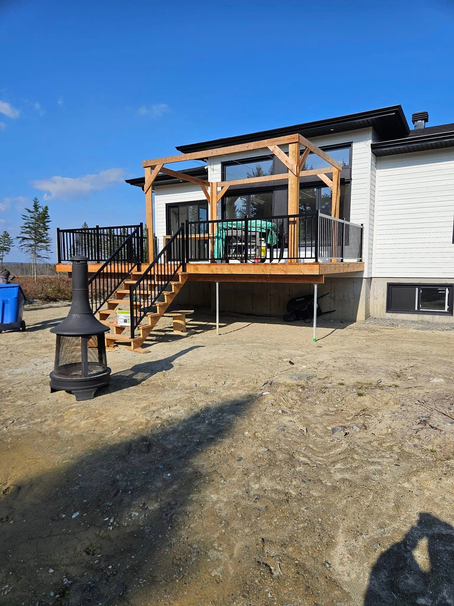 Une maison avec une terrasse en bois et des escaliers devant.