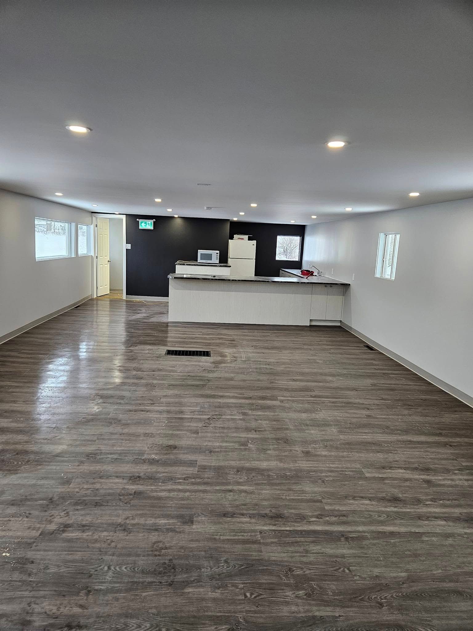 Une grande pièce vide avec un plancher en bois et des murs blancs.