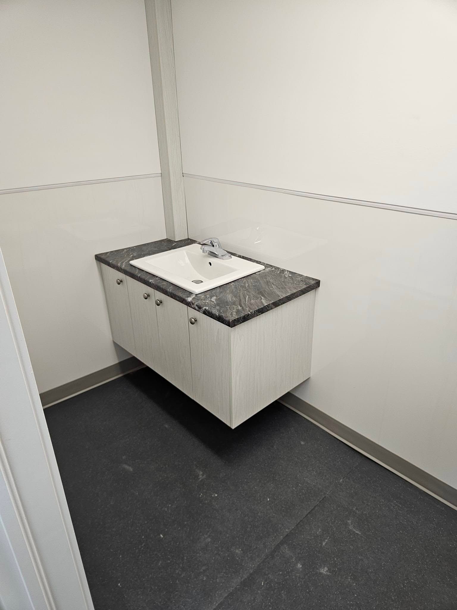 Une salle de bain avec un lavabo et un sol noir