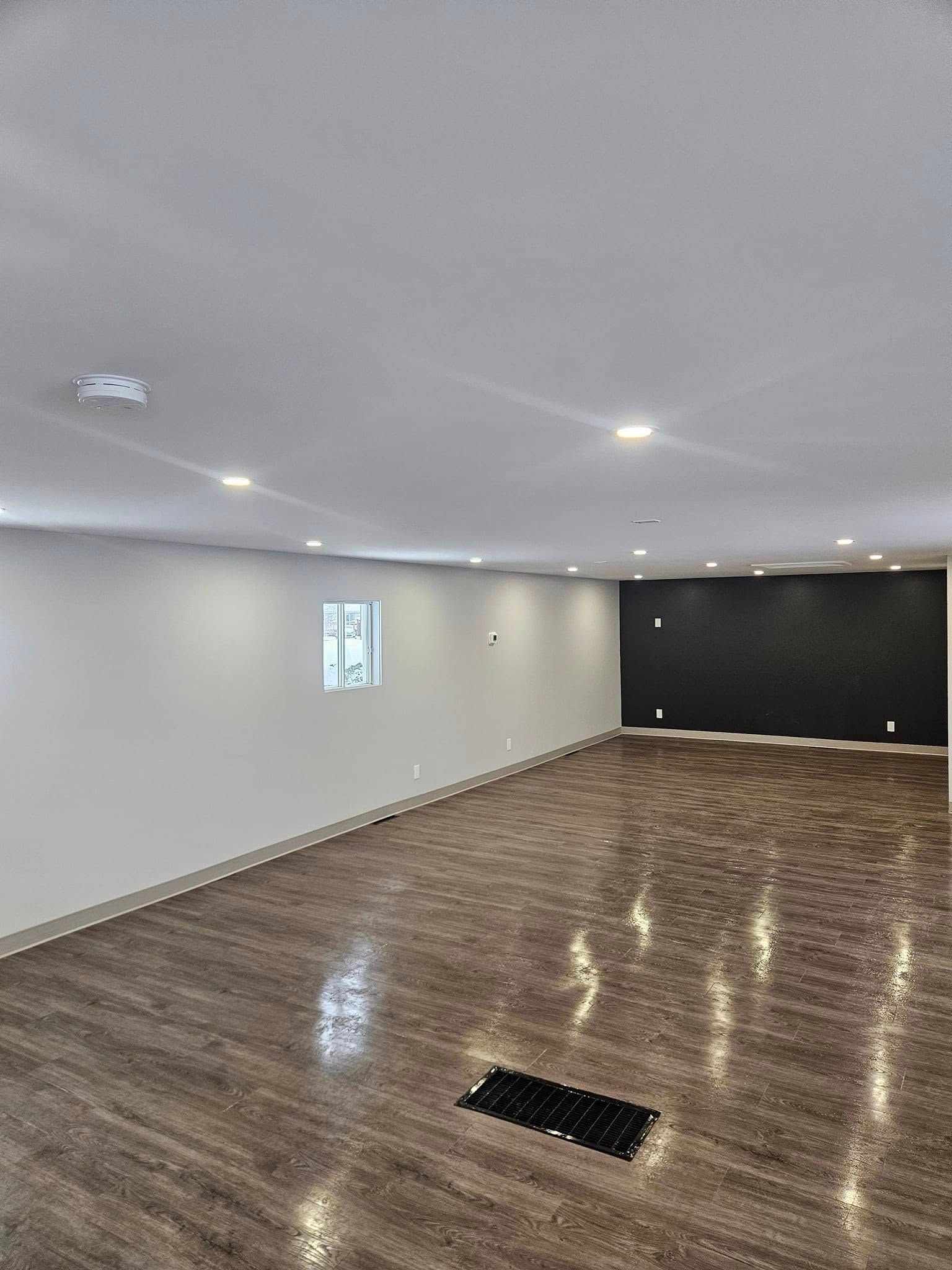 Une grande pièce vide avec du parquet et des murs blancs.