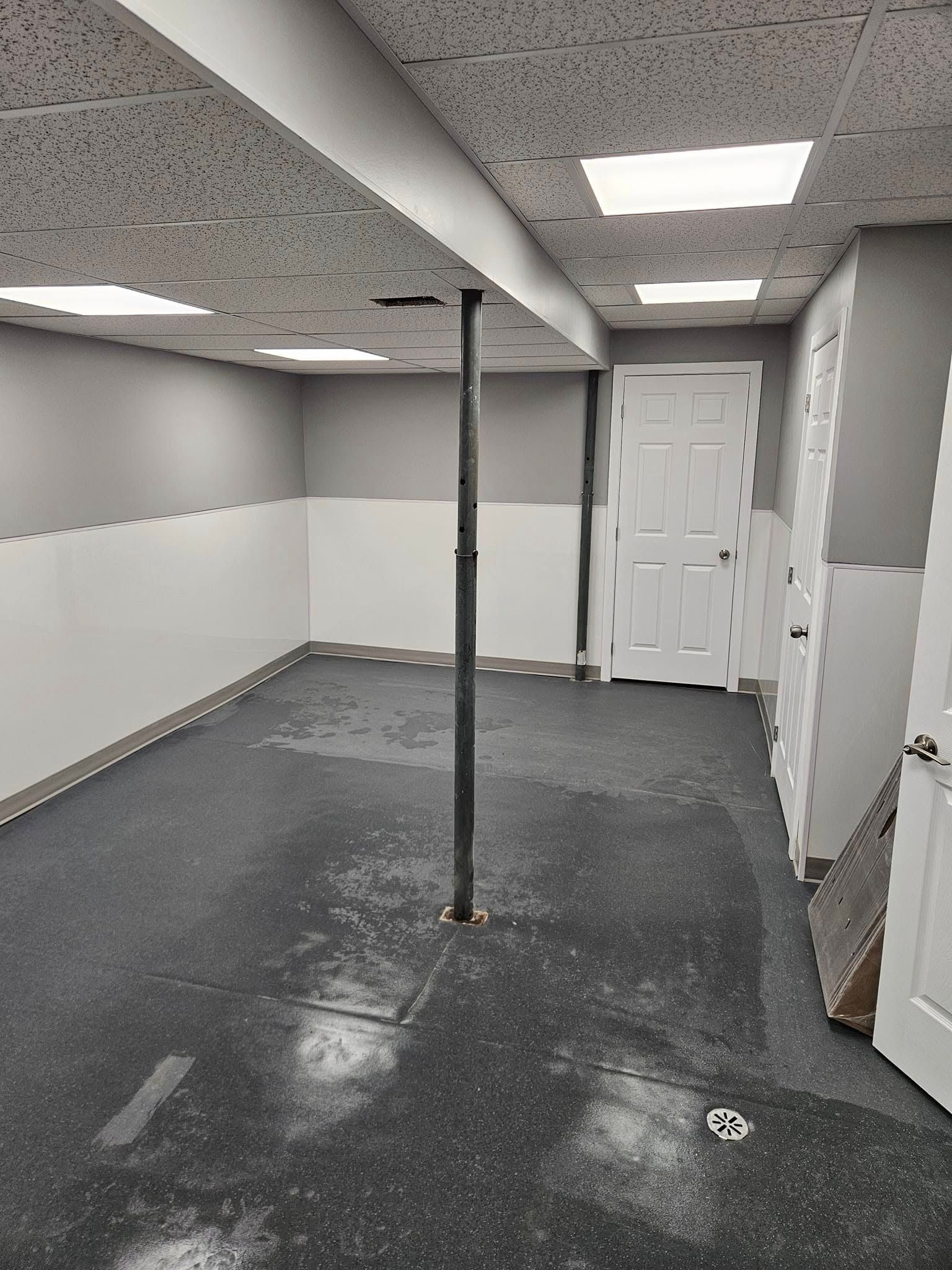 Un sous-sol vide avec un sol noir et des murs blancs.