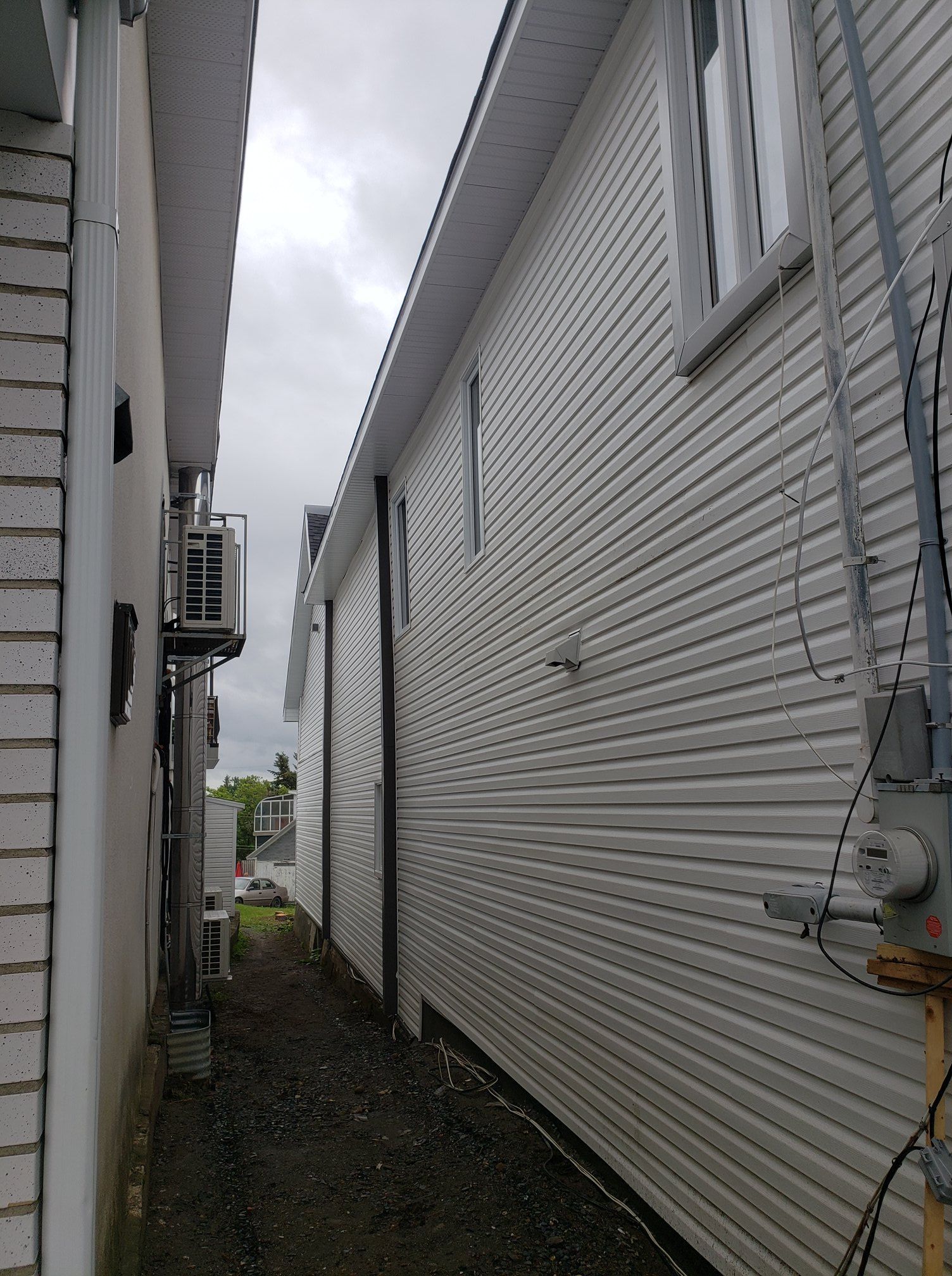 Une ruelle étroite entre deux bâtiments au revêtement blanc.