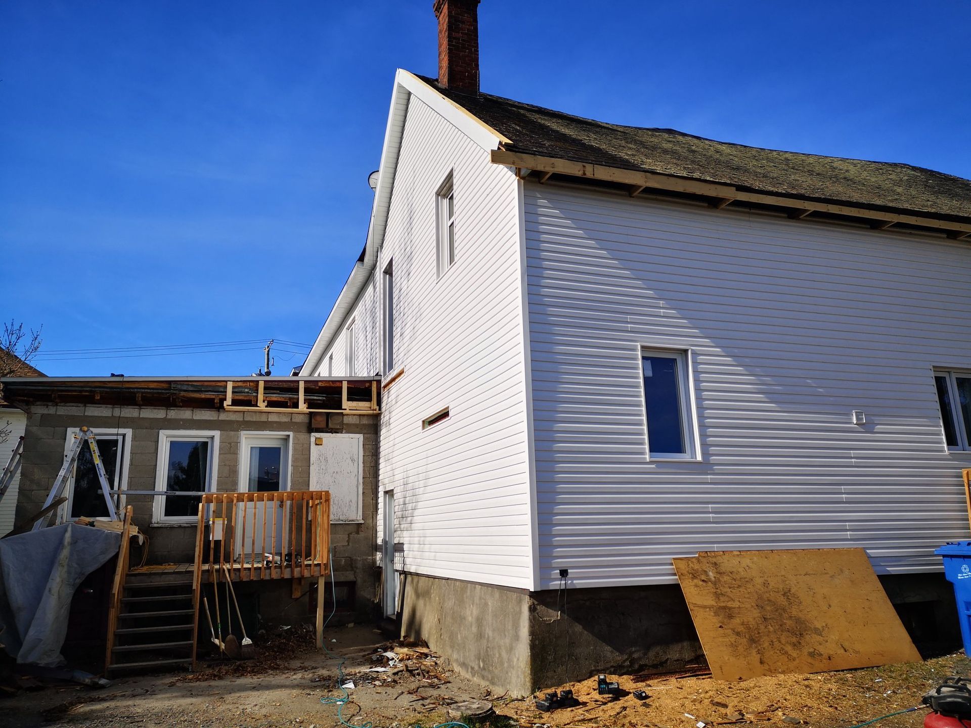 Une maison blanche avec une terrasse en bois est en cours de rénovation.