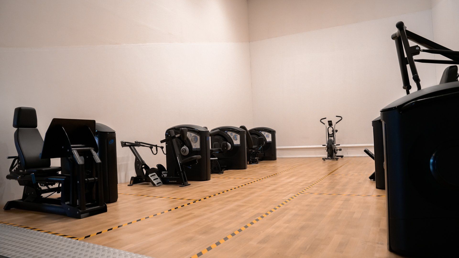 een sportschool met veel fitnessapparatuur op de vloer.