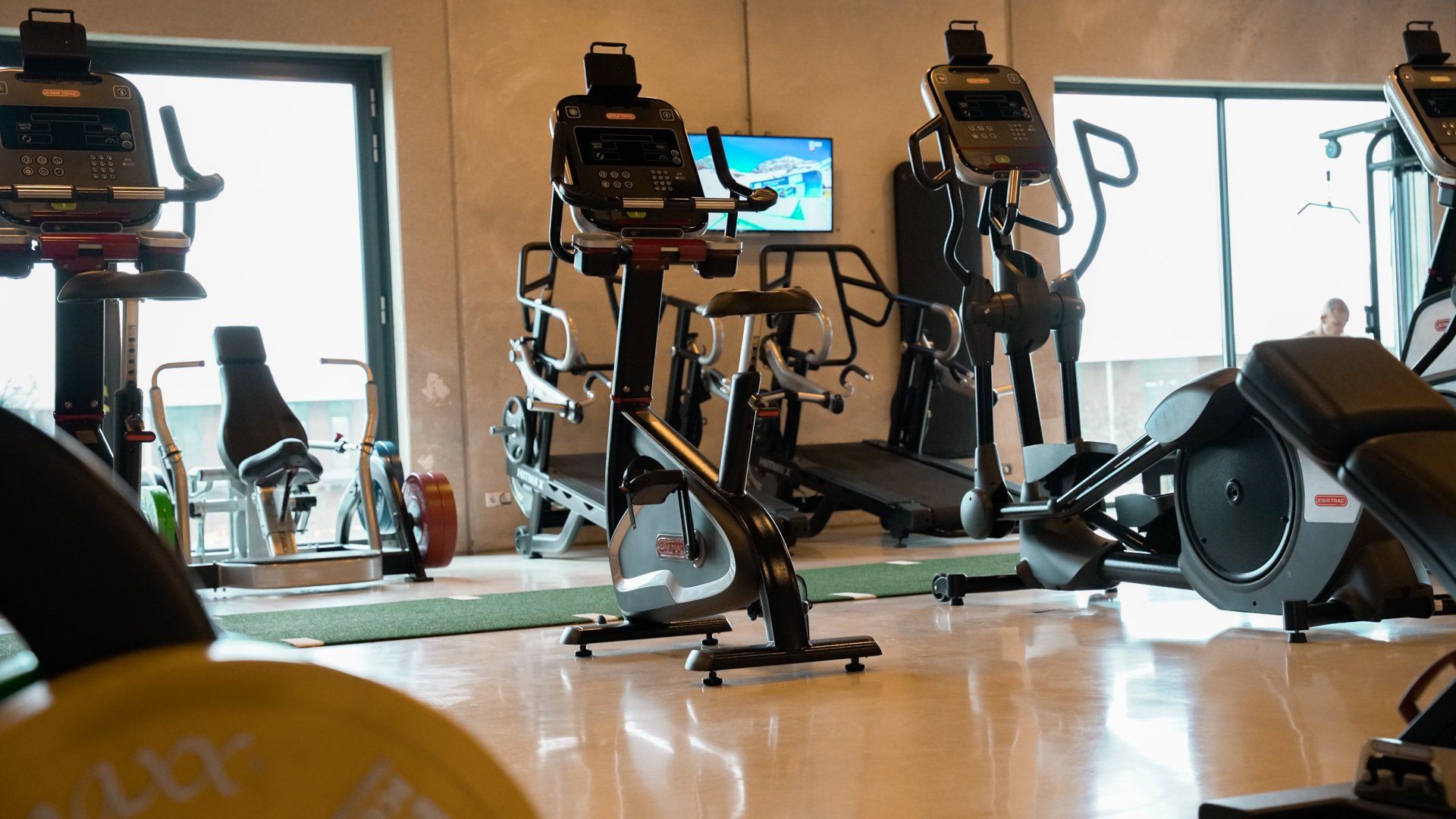 Sportschoolinterieur met fitnessapparatuur: loopbanden, crosstrainer, hometrainer en losse gewichten