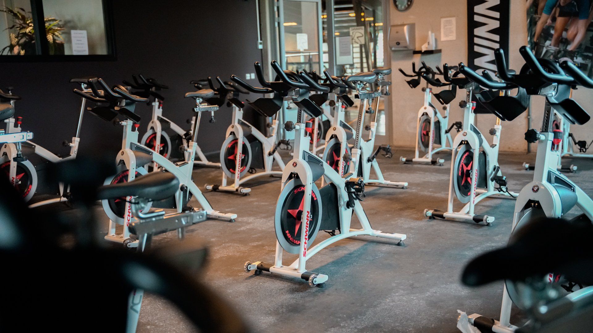 In een sportschool staat een rij hometrainers opgesteld.