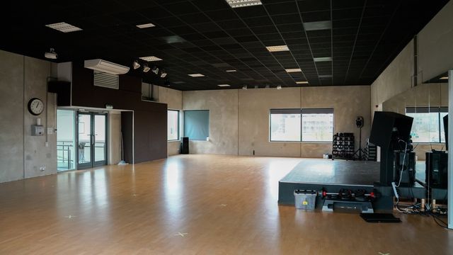 een lege dansstudio met een houten vloer en een spiegel.