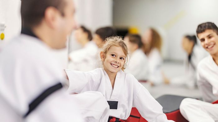 A group of children are sitting on the floor in a karate class.