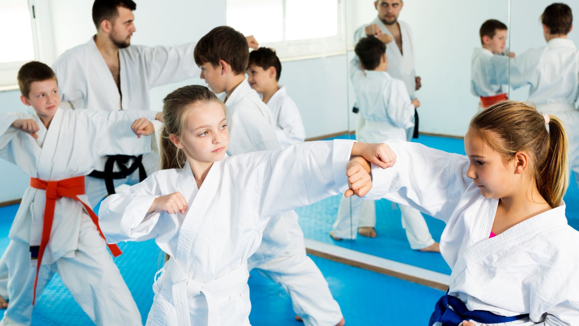 A group of children are practicing karate in a gym.