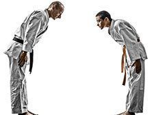 Two men in karate uniforms are bowing to each other.