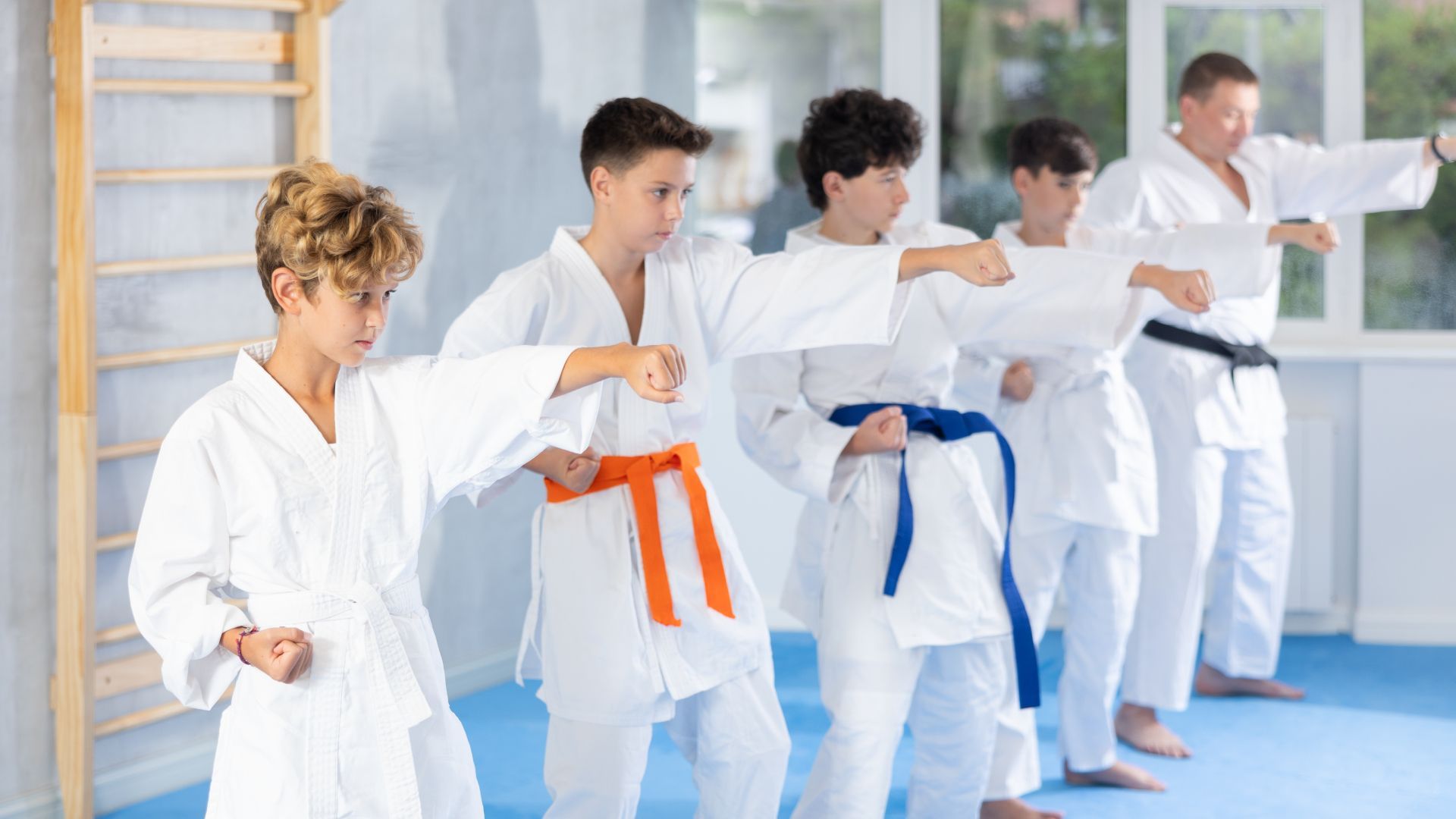 A group of young boys are practicing karate in a gym.